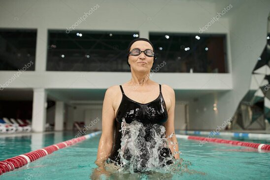 インストラクターの指導のもと温水プールで運動する高齢者たち